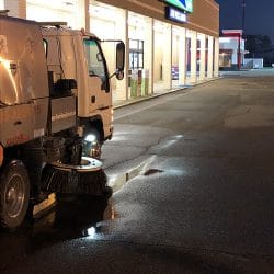 Street sweeping in retail parking lot with truck