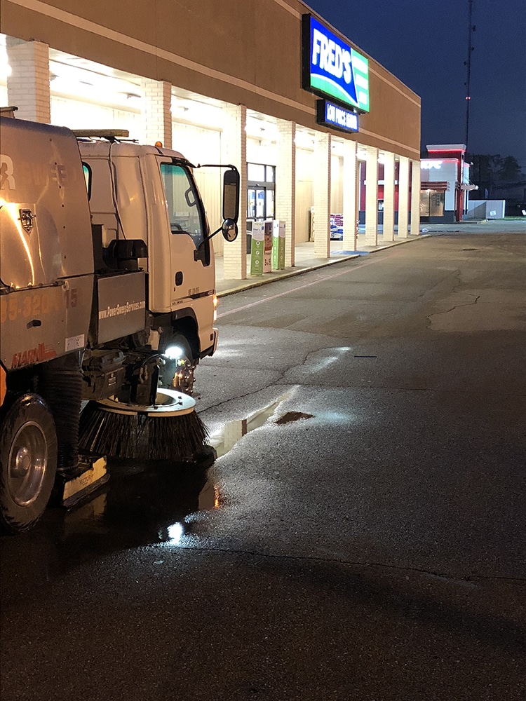Street sweeping in retail parking lot with truck