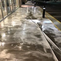 Power washing pavement in front of store